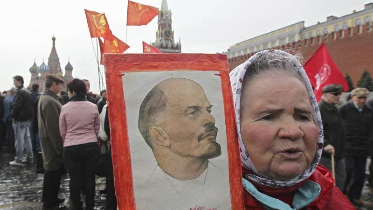 Una mujer sostiene una imagen de Lenin, líder de la revolución rusa, durante una ofrenda floral