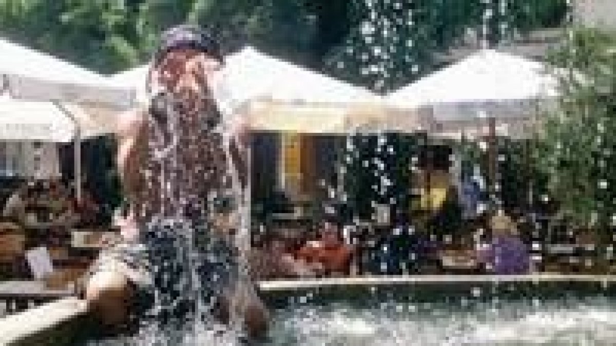 Un turista se refresca en una fuente para mitigar el fuerte calor