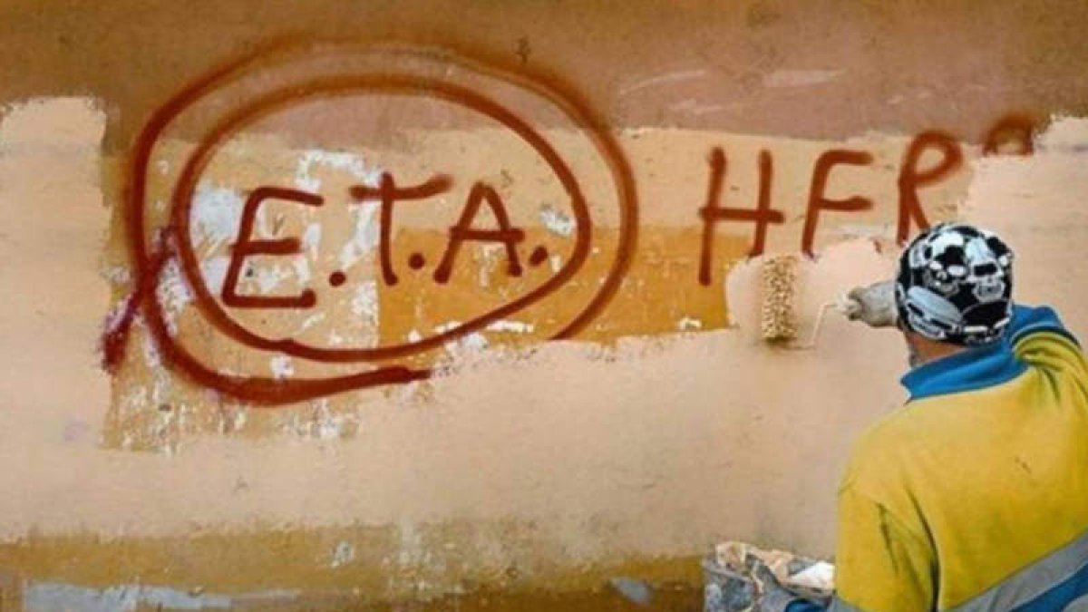 Una persona borra de una pared una pintada de apoyo a la banda terrorista que vive un triste final tras su derrota. DL