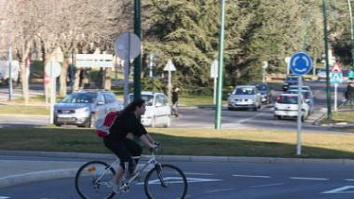 Una joven con su mochila pasa en bicicleta por el carril de la zona universitaria.