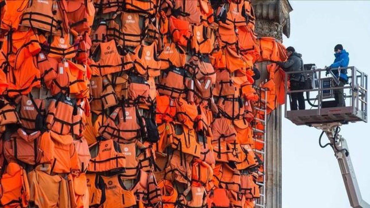 Asistentes del artista Ai Weiwei colocan chalecos salvavidas en la Kinzerthaus de Berlín, en recuerdo de los refugiados.