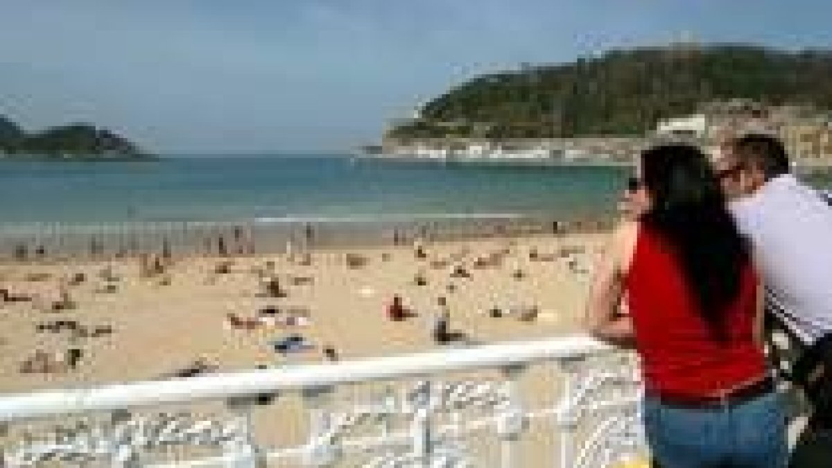 Unos turistas se asomam a la playa de la Concha en San Sebastián