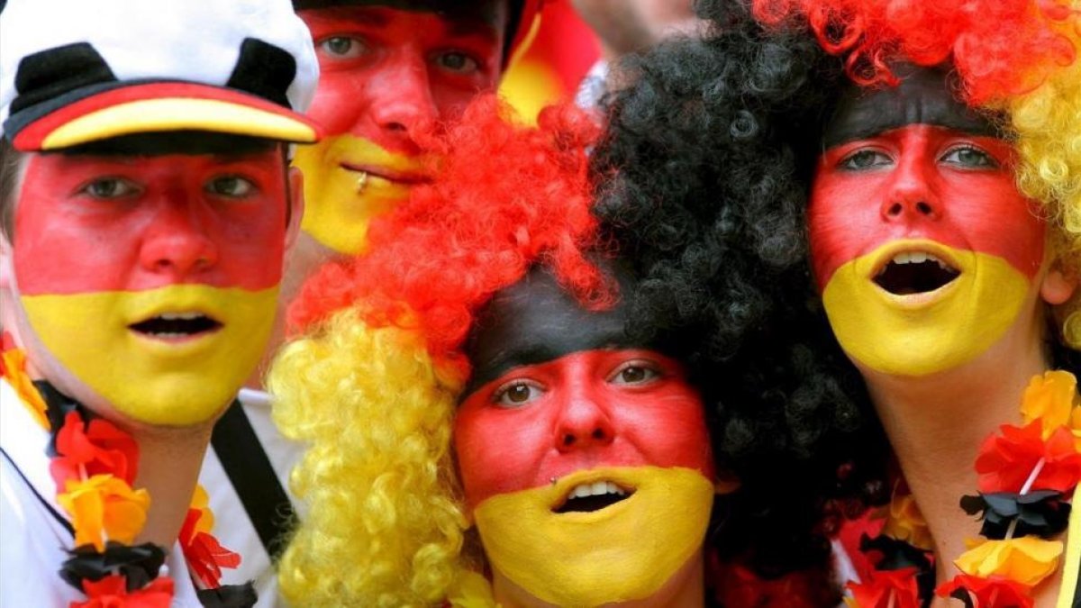 Aficionados alemanes animan a su seleccion en un partido de fútbol.
