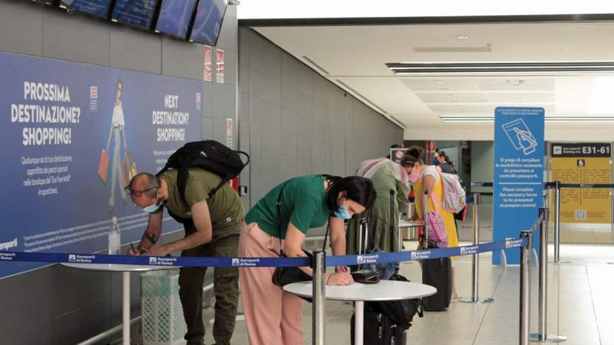 Viajeros rellenan papeles sobre el covid en el aeropuerto de Fiumicino, Roma.