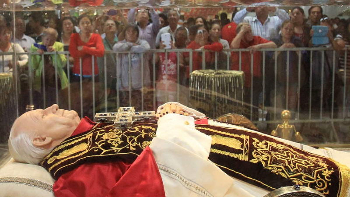 Fieles oran ante una imagen del papa Juan Pablo II.