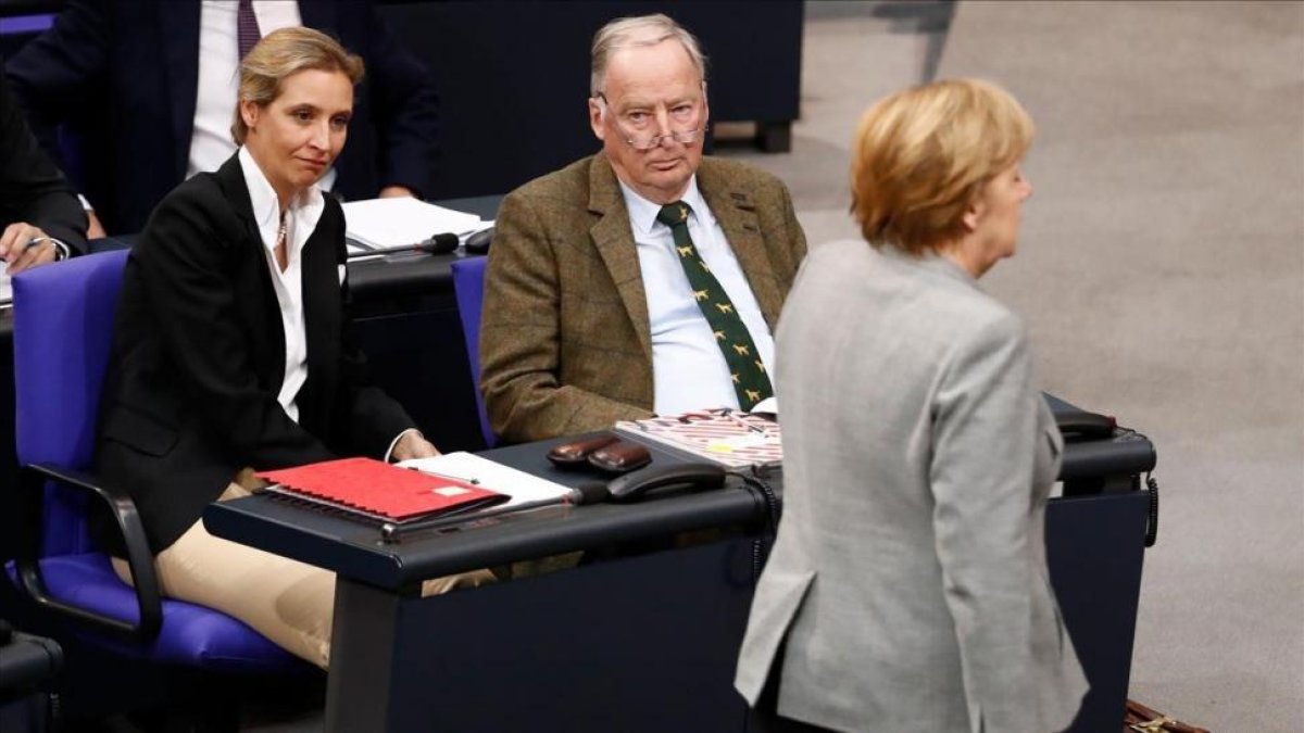 El cancillera Angela Merkel pasa frente a dos de los dirigentes de AfD, Alexander Gauland y Alice Weidel, en el Parlamento alemán.