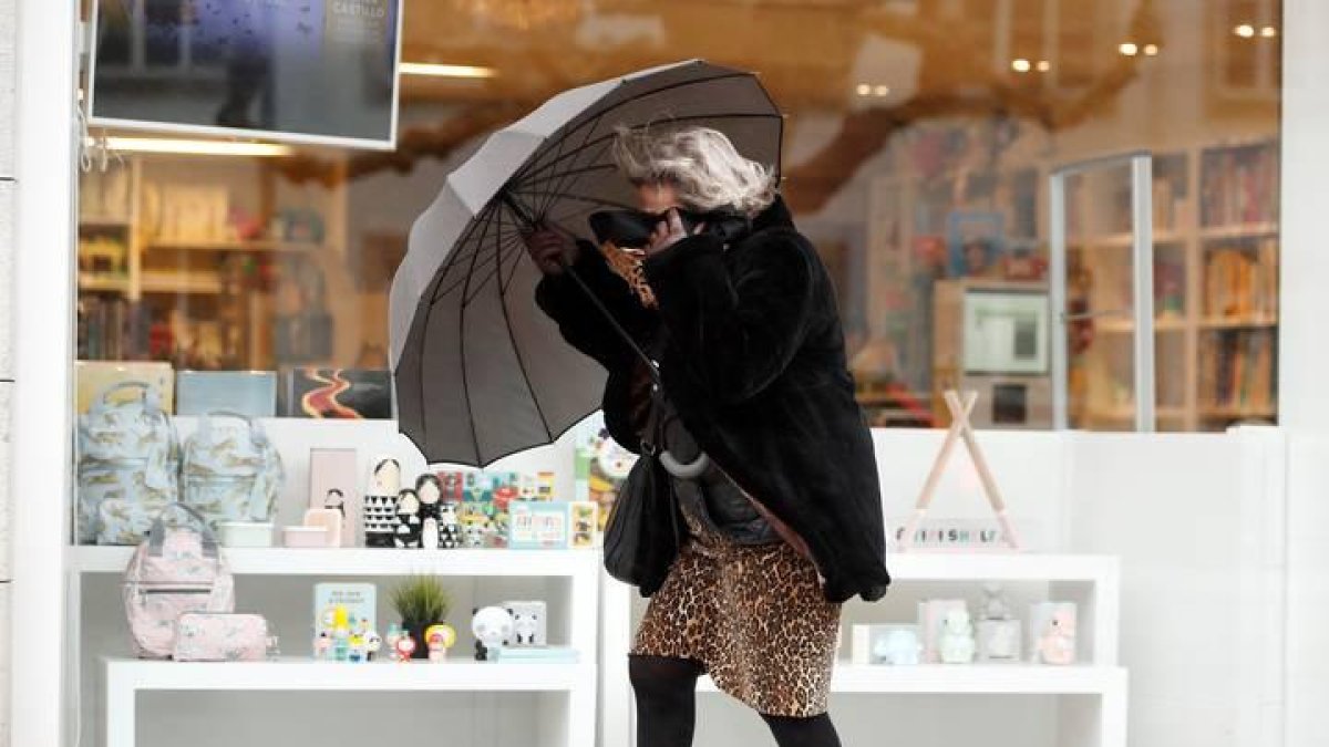 Una mujer se resguarda del viento y la lluvia