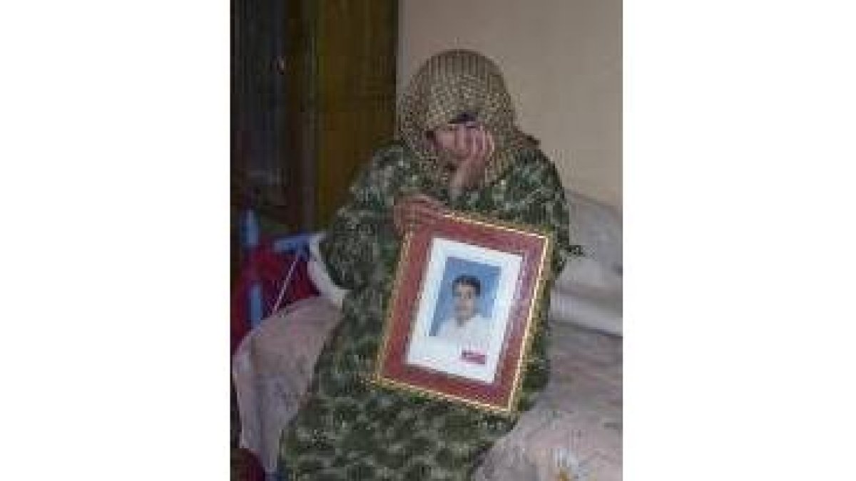 Zeinab Wali, madre de El Egipcio, posa con un retrato de éste en el interior de su casa en Aziziya