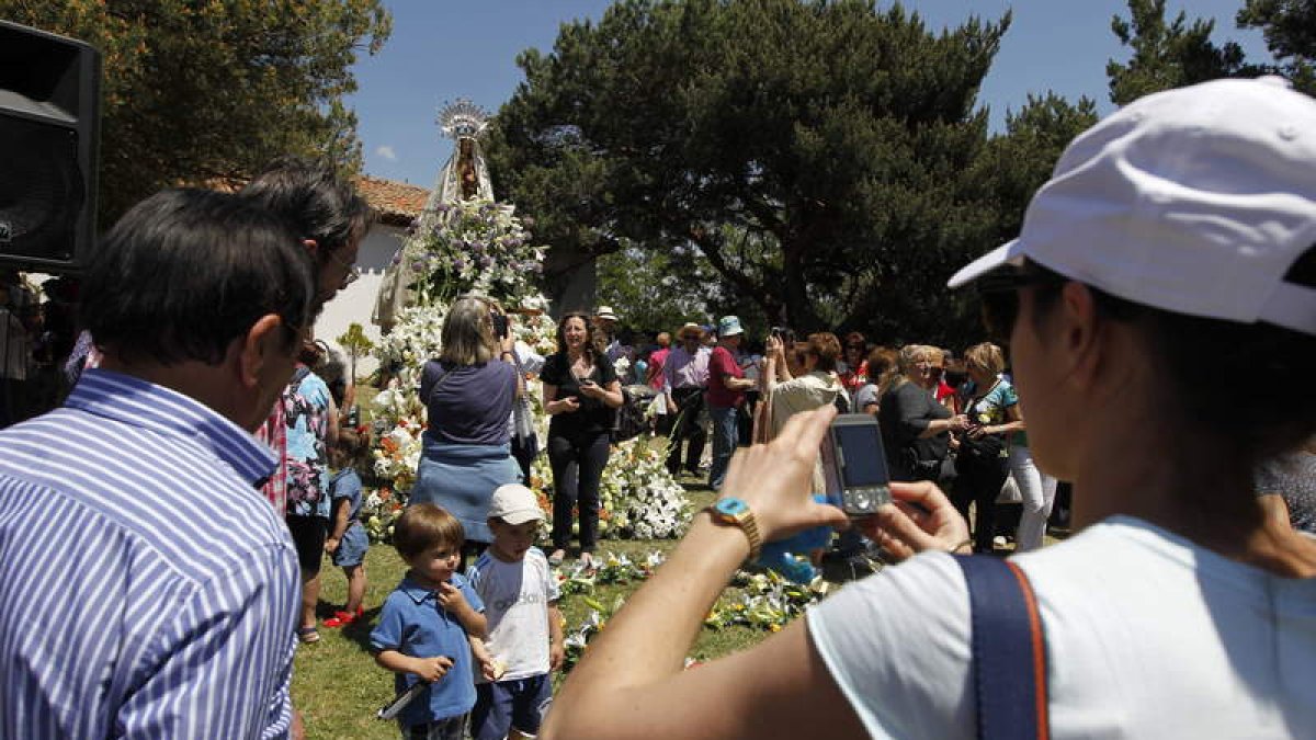 Todos quieren hacerse fotos con el trono de flores de la Virgen del Villar.