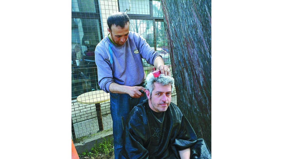 Un refugiado corta el pelo al leonés Ricardo Valderrama en el asentamiento de Idomeni.