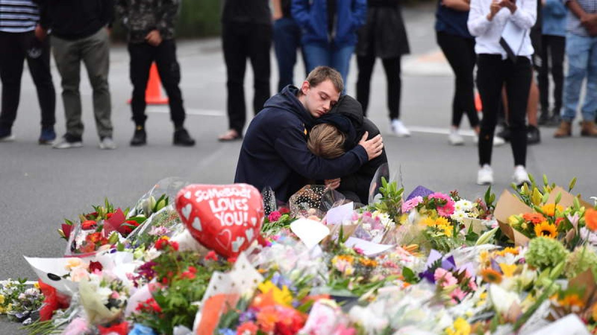 Dos jóvenes ante las flores en recuerdo de las víctimas del distrito de Christchurch. MICK TSIKAS