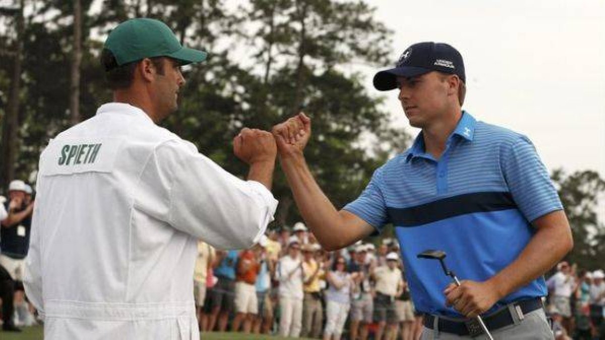 Jordan Spieth y su 'caddie' chocan los puños durante la primera jornada del Masters de Augusta.
