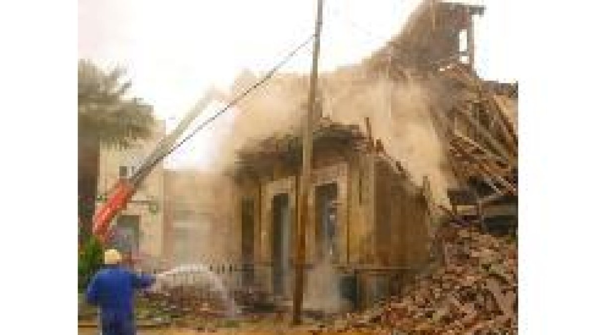 Un obrero arroja agua con una manguera durante la demolición