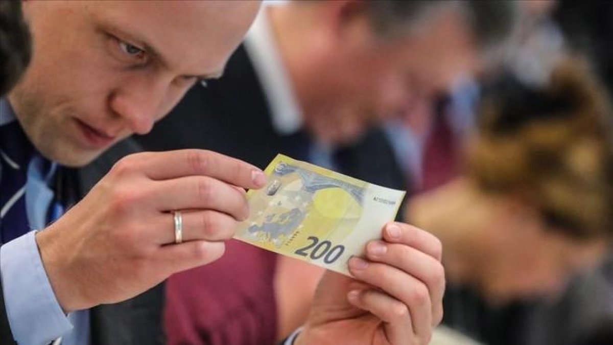Un periodista inspecciona un nuevo billete de 200 euros, presentados este lunes.