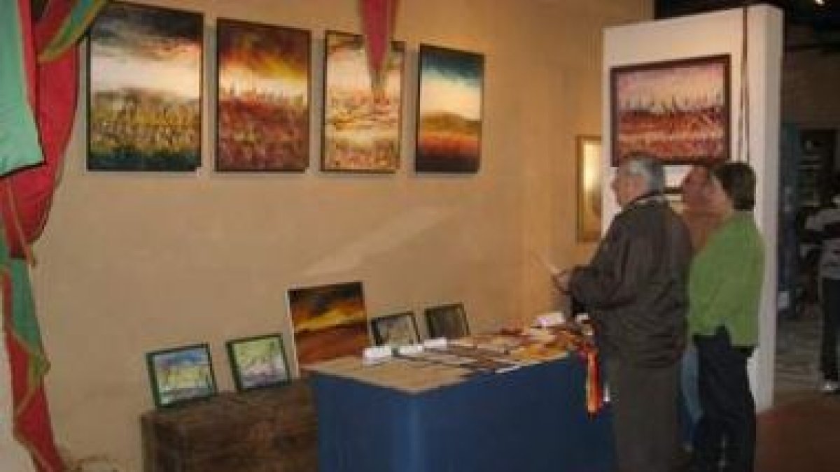 Varios visitantes contemplan parte de la exposición en La Comunal