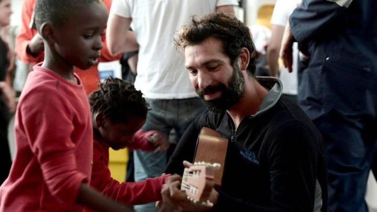Un voluntario de Médico Sin Fronteras toca la guitarra junto a un niño