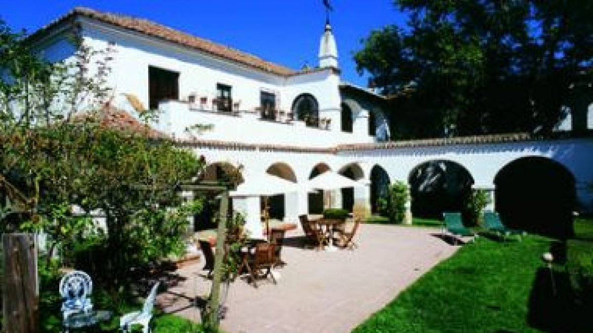 El encantador jardín, una habitación con camas con dosel y un salón de La Posada del Marqués.