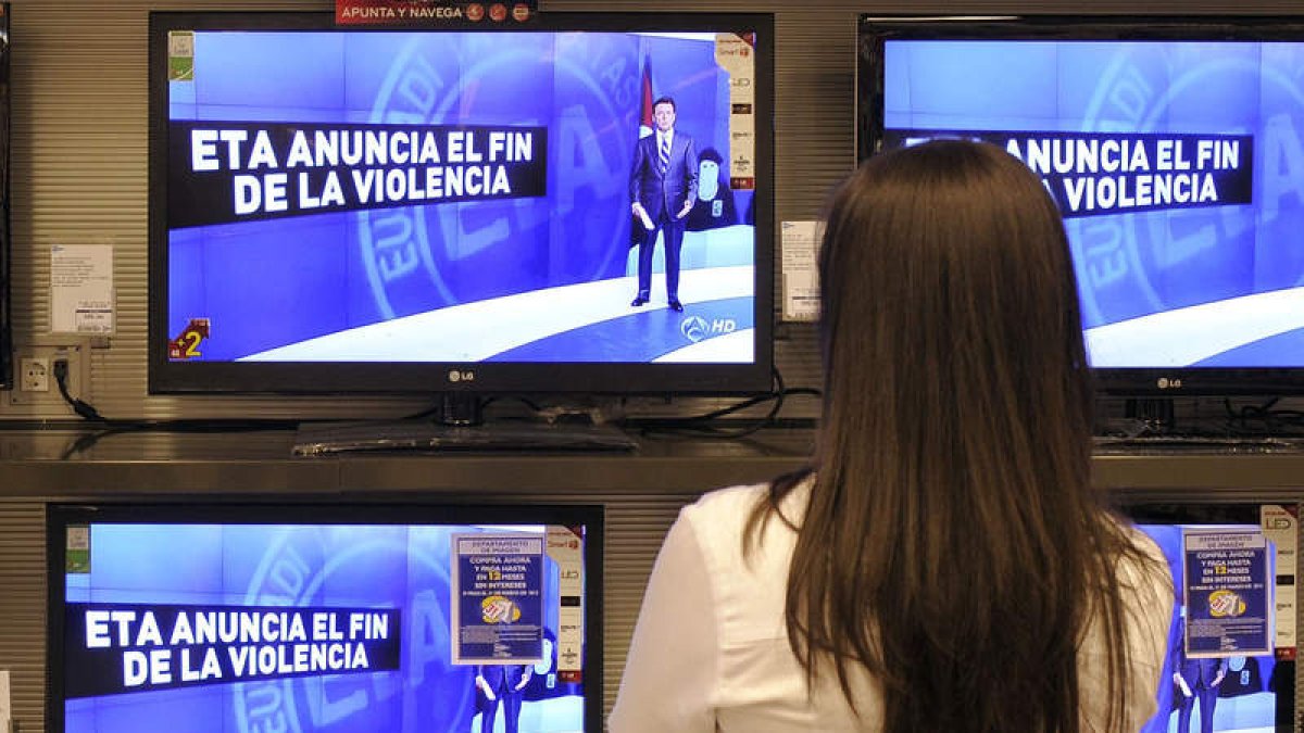 Una mujer observa en las televisiones el anuncio del fin de la violencia el año pasado.