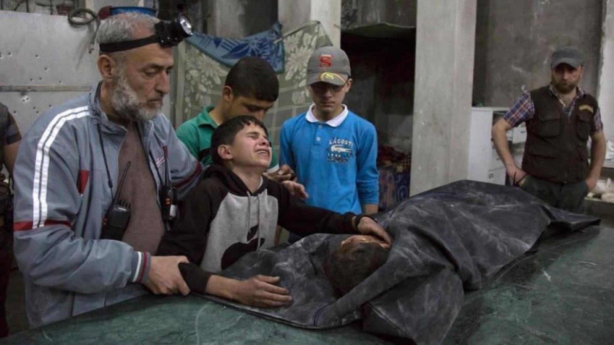 Un niño sirio es consolado mientras llora junto al cuerpo de su hermano pequeño que murió en el ataque aéreo del régimen de Bashar al Asad al hospital de Al Quds.