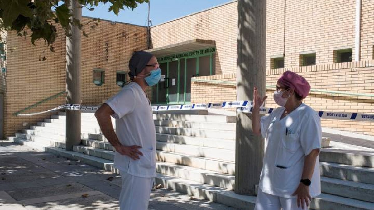 Dos sanitarios conversan en las inmediaciones del polideportivo Cortes de Aragón de Fraga, Huesca este martes donde se encuentran algunos enfermos con coronavirus. JAVIER BLASCO