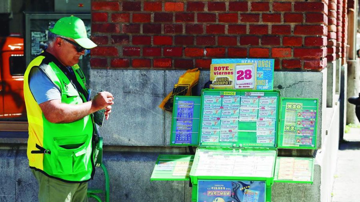 Un vendecor de la Once, junto a su puesto de venta de productos de juegos en León.