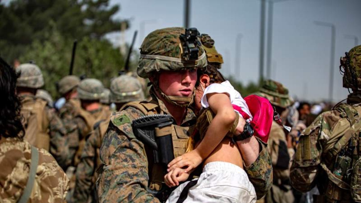 Imagen de un marine con un niño afgano herido. EFE