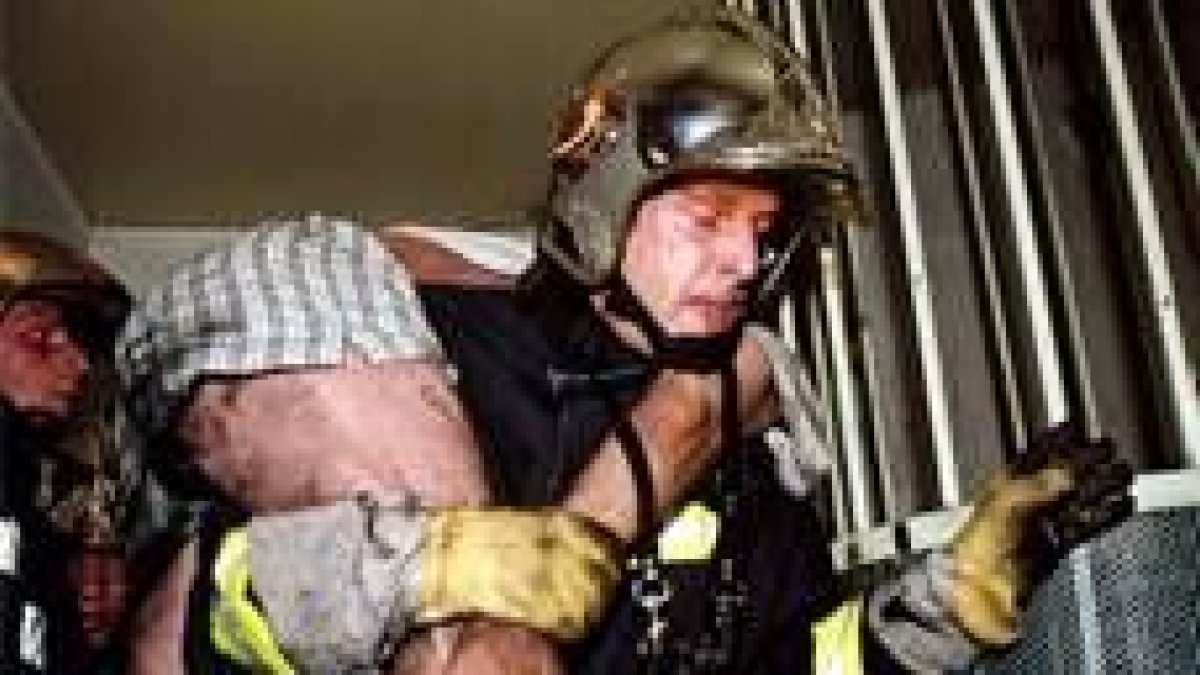 Un bombero evacúa del edificio parisino a uno de los heridos en el incendio de ayer