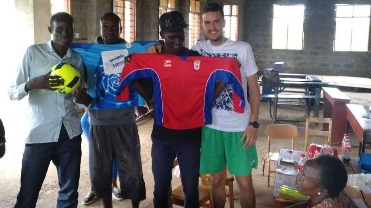El entrenador de la Peña A cadete, Borja García, entrega el material deportivo peñista en Uganda. DL
