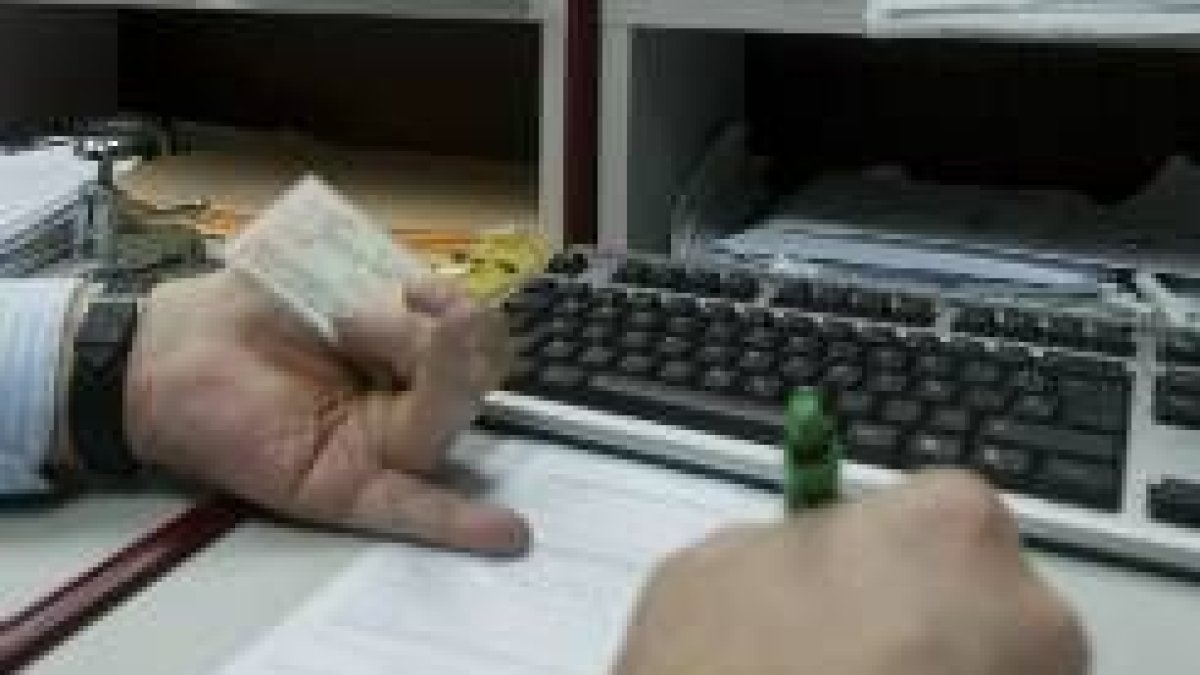 Un funcionario procede a comprobar los datos de un contribuyente en una gestión de pago de impuestos