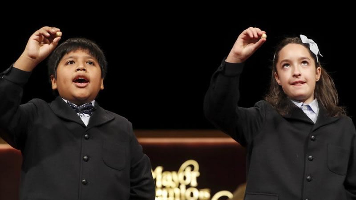 Los niños de San Ildefonso Nerea y Daniel muestran las bolas con el primer cuarto premio que ha recaido en el número 59.444.