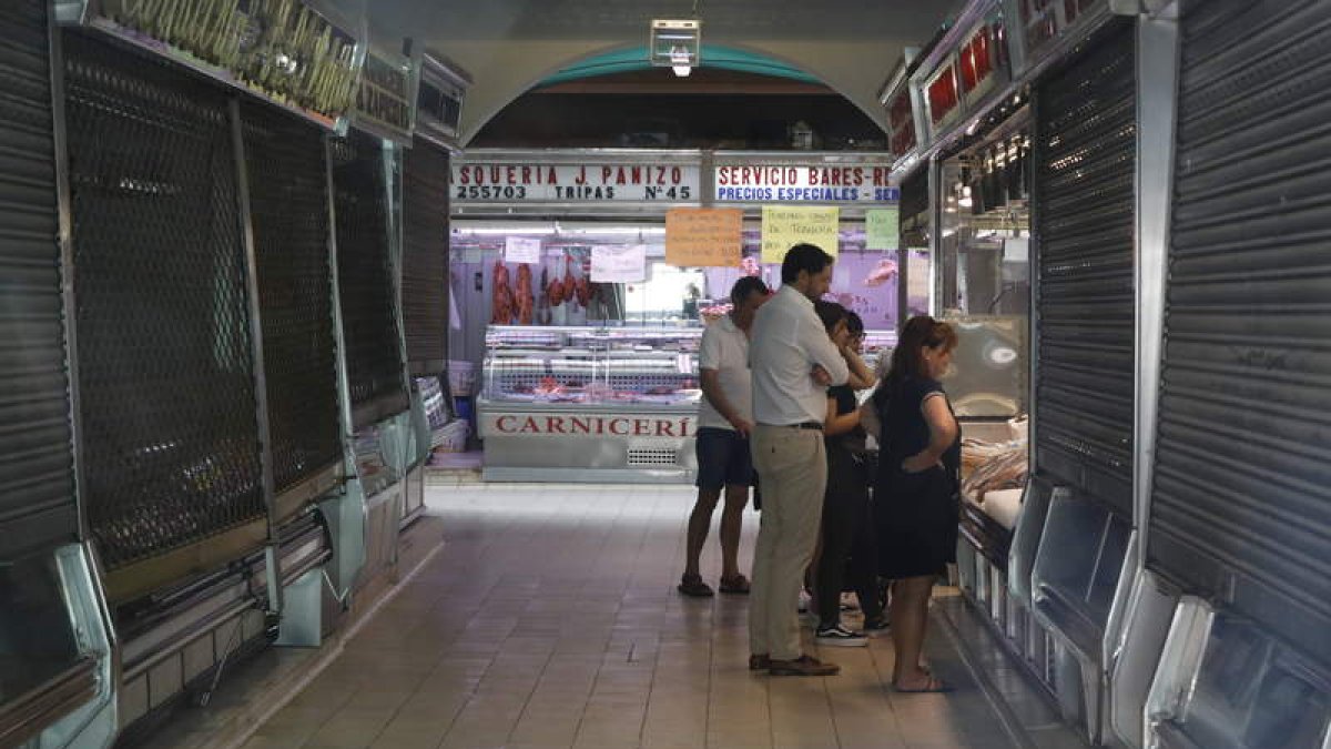 Clientes ayer en uno de los apenas 21 puestos que quedan abiertos en el mercado. MARCIANO PÉREZ