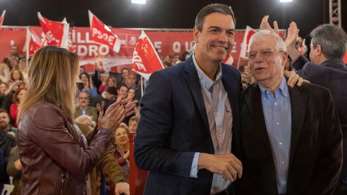 El presidente del Gobierno, Pedro Sánchez, saluda al ministro de Exteriores, Josep Borrell durante el mitin que han celebrado en Sevilla. A la izquierda, Susana Díaz, secretaria general de los socialistas andaluces.