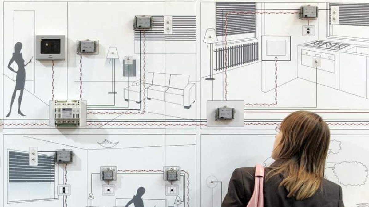 Una mujer contempla un panel que muestra cómo funciona una casa domotizada.