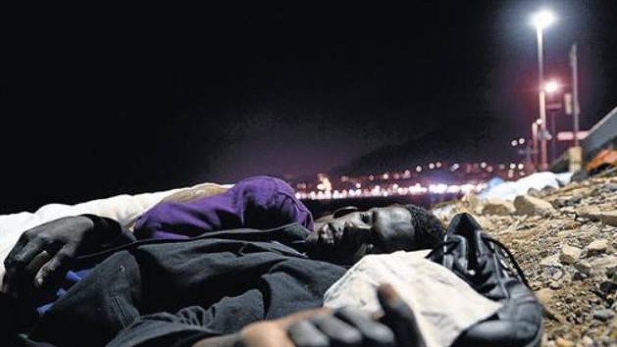 Un inmigrante africano duerme en el suelo, sobre unas piedras, cerca del mar en Ventimiglia, este lunes.