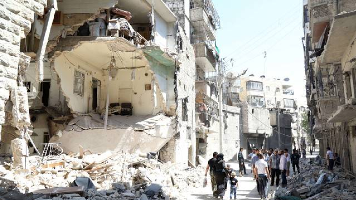 Vecinos de Alepo pasan junto a un edificio destruido en un bombardeo del régimen, este domingo.