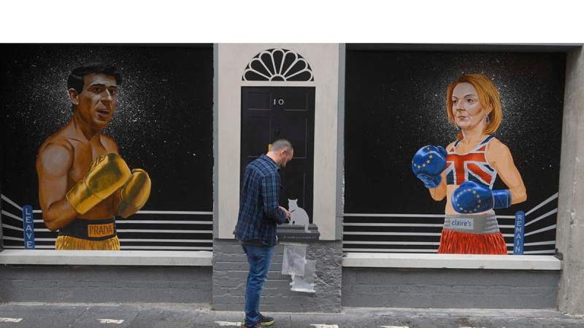 Ciaran Gallagher da los toques finales a su mural en Belfast con Rishi Sunak y Liz Truss separados por el 10 de Downing Street. MARK MARLOW