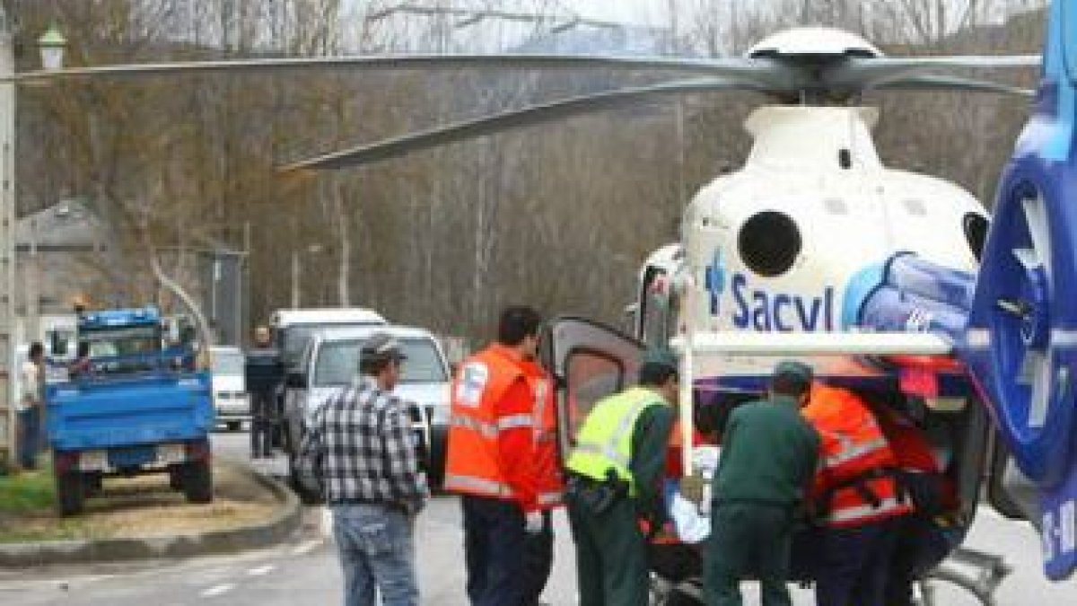 El joven de 28 años es introducido en el helicóptero. A la izquierda, el tractor que conducía.