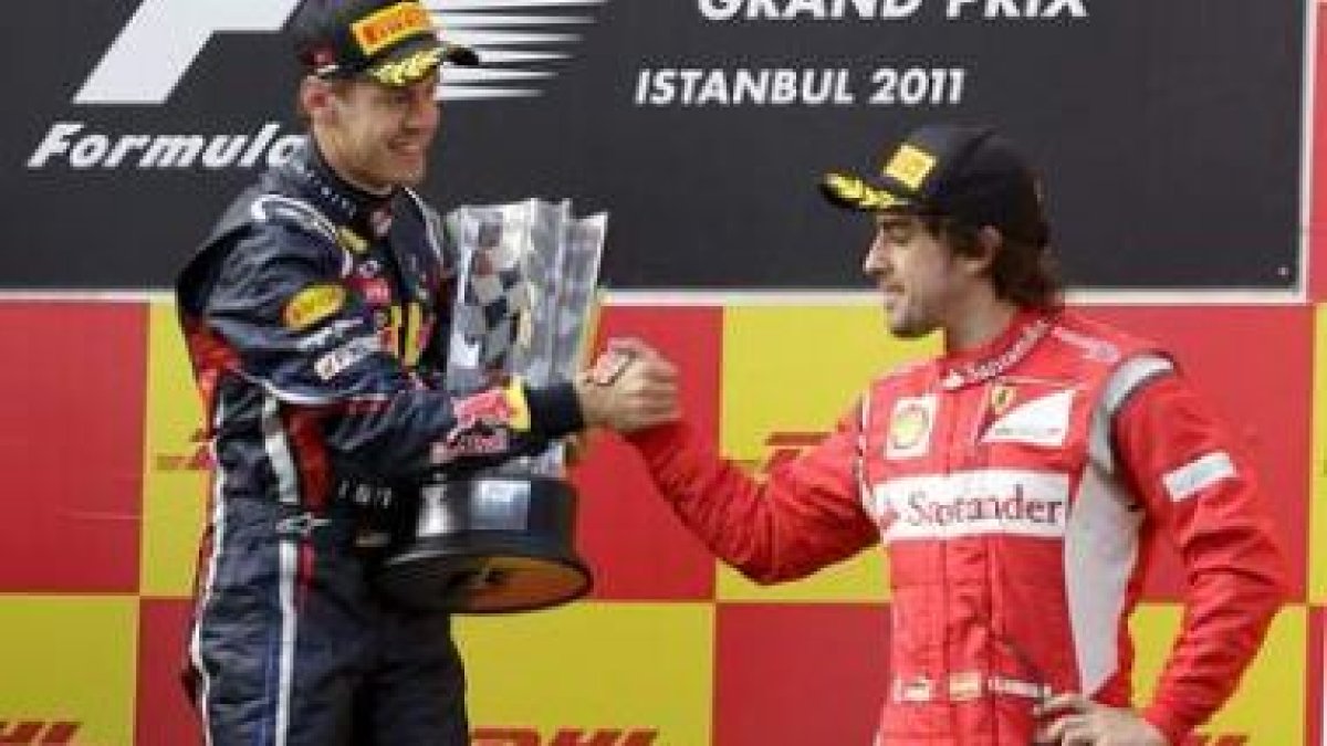 Fernando Alonso, de la escudería Ferrari, estrecha la mano del alemán Sebastian Vettel, en el podio.