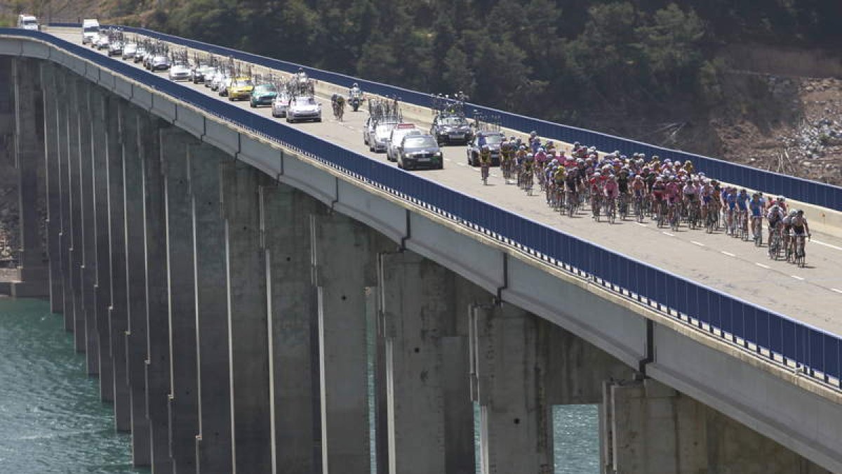 El pelotón, con todos los coches de avituallamiento y apoyo detrás, a su paso por el puente sobre el embalse de Riaño.