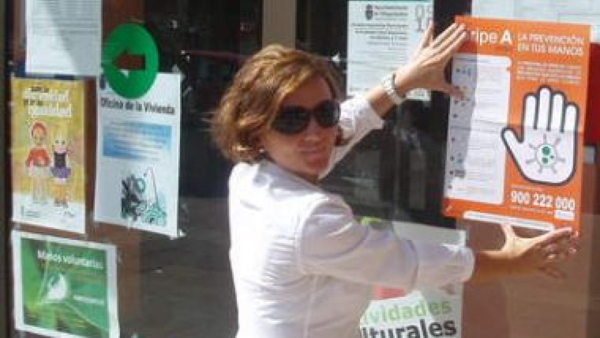 Milagros Gordaliza pega un cartel informativo de la gripe A.