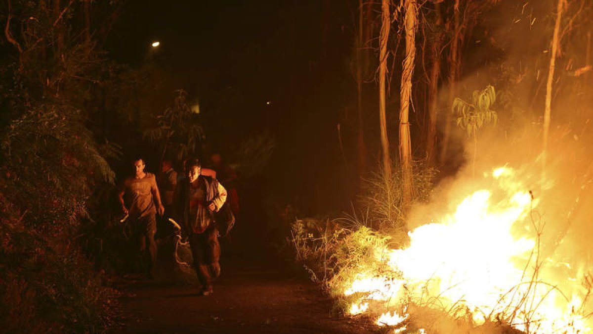 Varios vecinos intentan sofocar las llamas del incendio forestal de Arbo (Pontevedra). SXENICK
