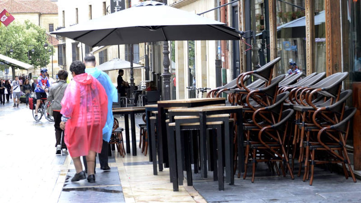 Turistas protegidos contra la lluvia en la calle Ancha, donde las terrazas estaban ayer recogidas por el mal tiempo