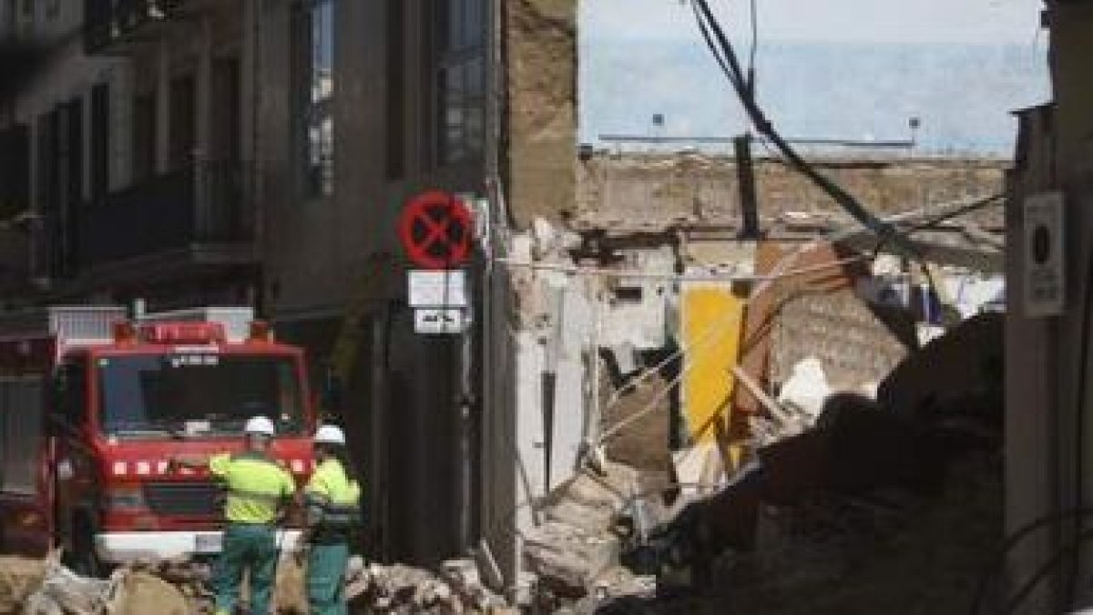 Varios bomberos trabajan entre los escombros.