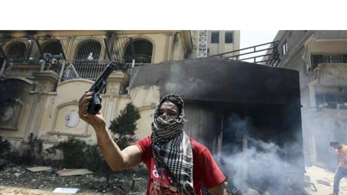 Un opositor a Mursi muestra una pistola hallada en la sede incendiada de los Hermanos Musulmanes, este lunes en El Cairo.
