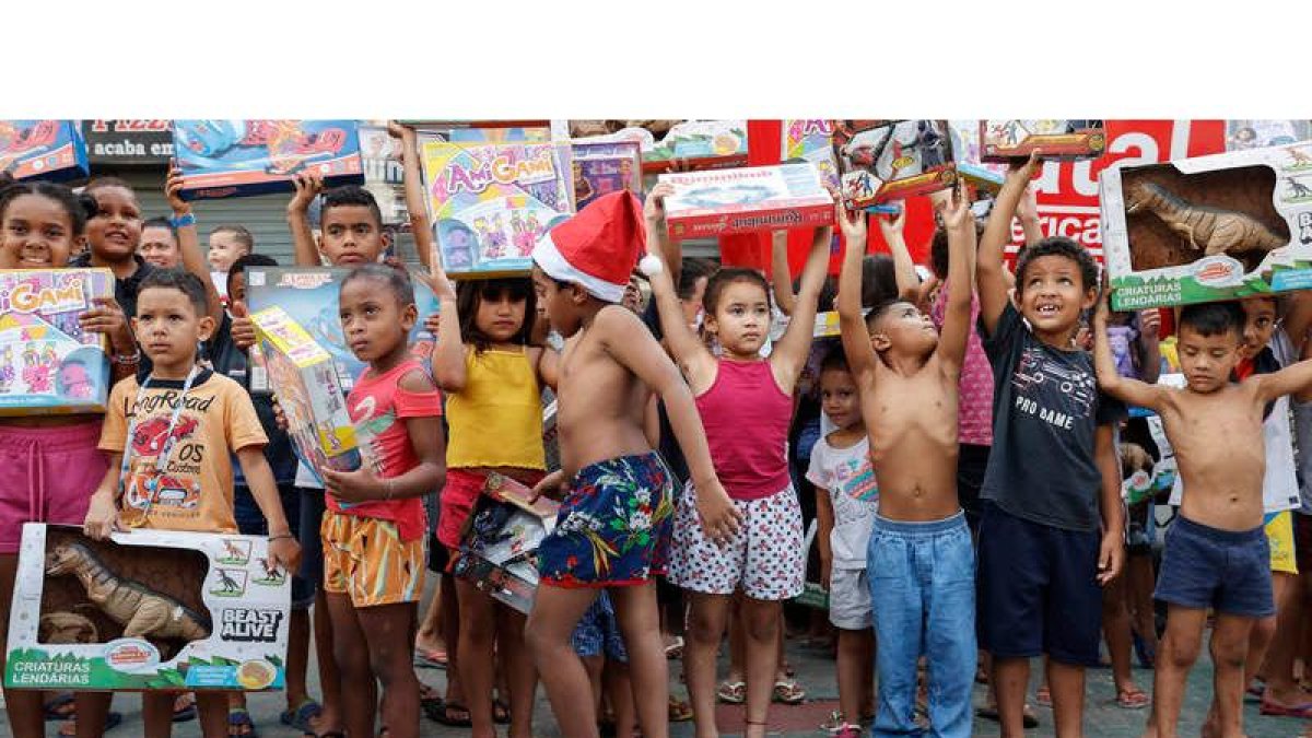 Niños posan para una fotografía con los regalos que recibieron para celebrar una Navidad. SEBASTIAO MOREIRA
