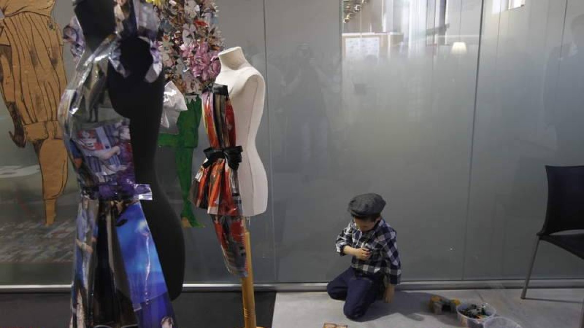 Un niño vestido al estilo de los años 50 y rodeado de cromos de la época.