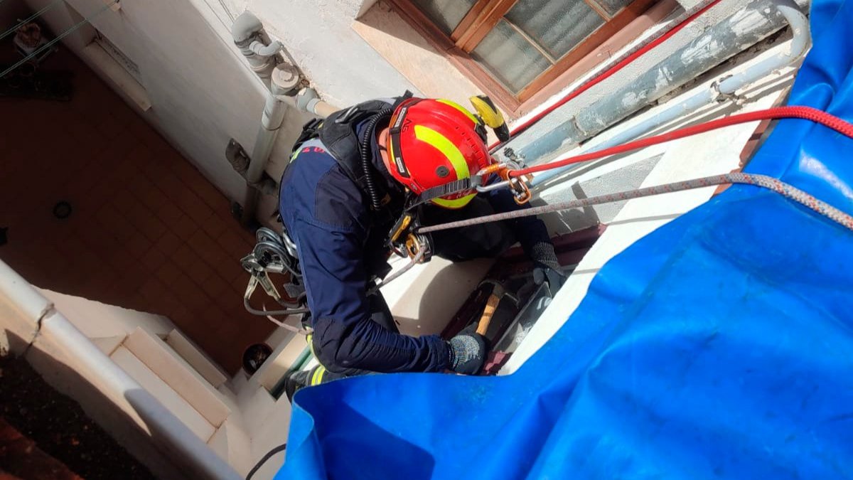 Uno de los bomberos desciende con cuerdas por un patio interior para socorrer a una anciana atrapada en su bañera. BOMBEROS DE LEÓN