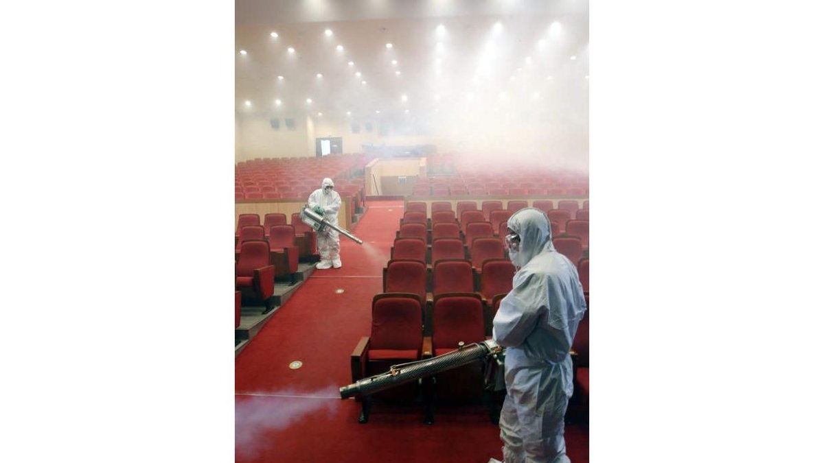 Dos operarios fumigan un salón de actos en Seúl.