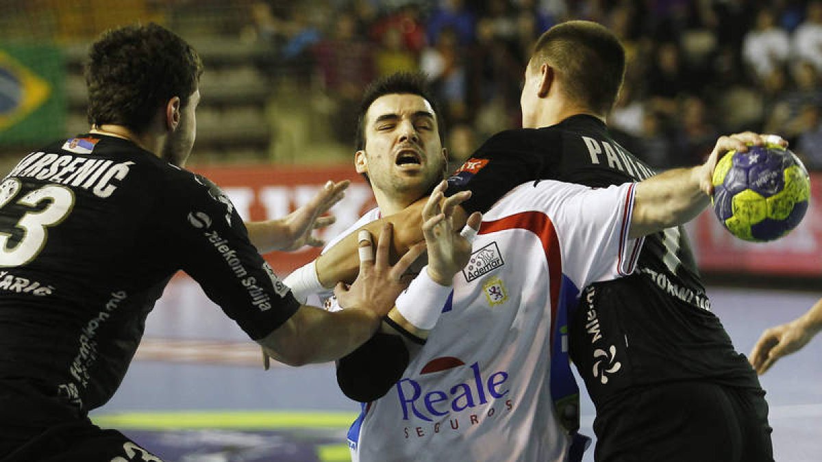 El jugador asturiano Carlos Ruesga, máximo goleador del partido, intenta un lanzamiento ante la oposición de Marsenic y Pavlovic.