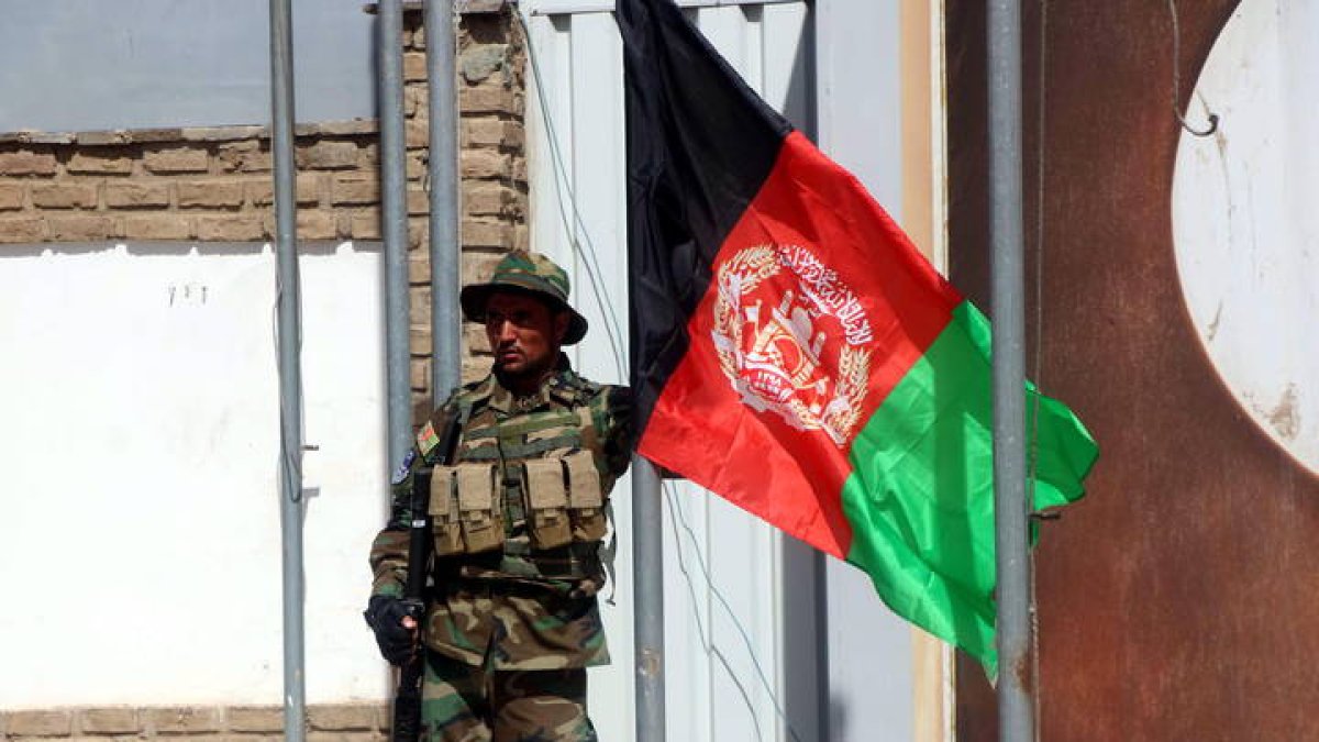 Soldado afgano izando una bandera de Afganistán en Camp Arena, base entregada por Italia en 2020. EFE/ JALIL REZAYEE